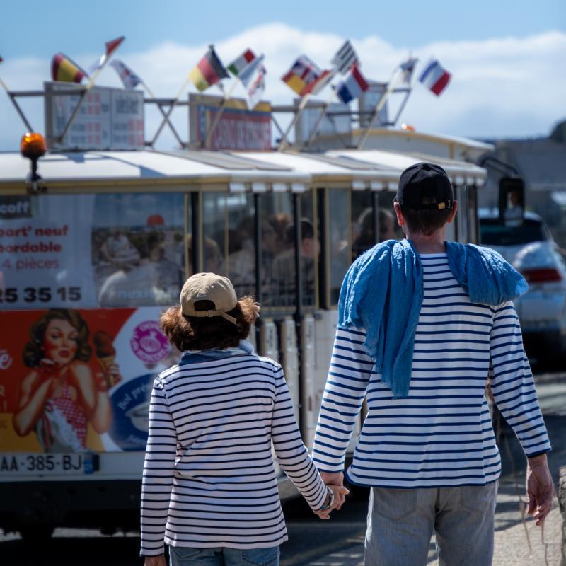 Un couple main dans la main vêtus de marinières vus de dos