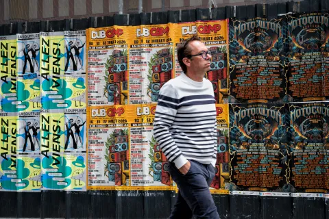 Homme passant devant un mur d'affiches
